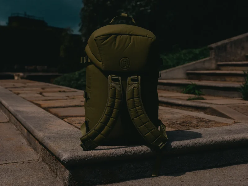 Dunkelolivfarbener Trainingsrucksack auf einer Steinstufe im weichen Tageslicht